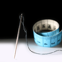 Photograph of needle, thread, and measuring tape used by tailor.