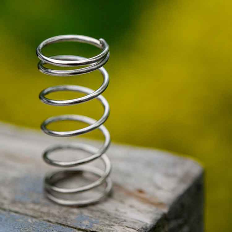 A close up photo of a metal spring against grass.