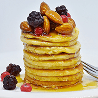 Photograph of a stack of pancakes with toppings.