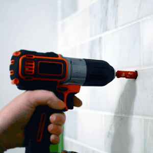 Image of a hand holding a drill, drilling tile.