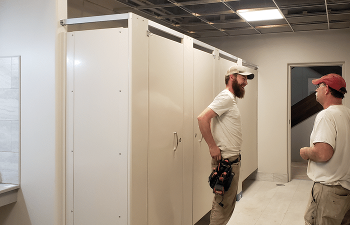 Photograph showing two installers standing near Hadrian Elite Plus toilet partitions.