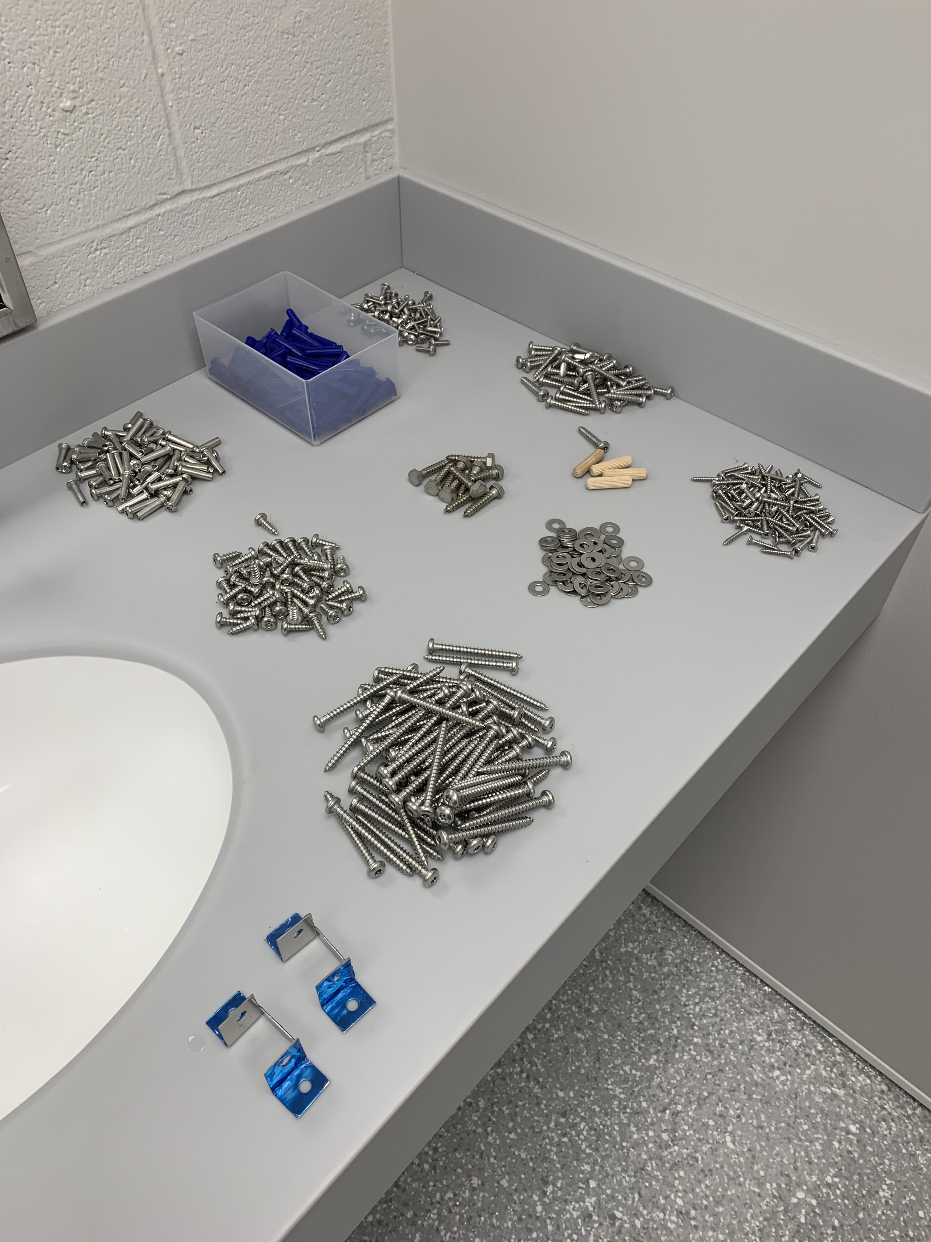 Photo of hardware for a bathroom stall installation separated into piles
