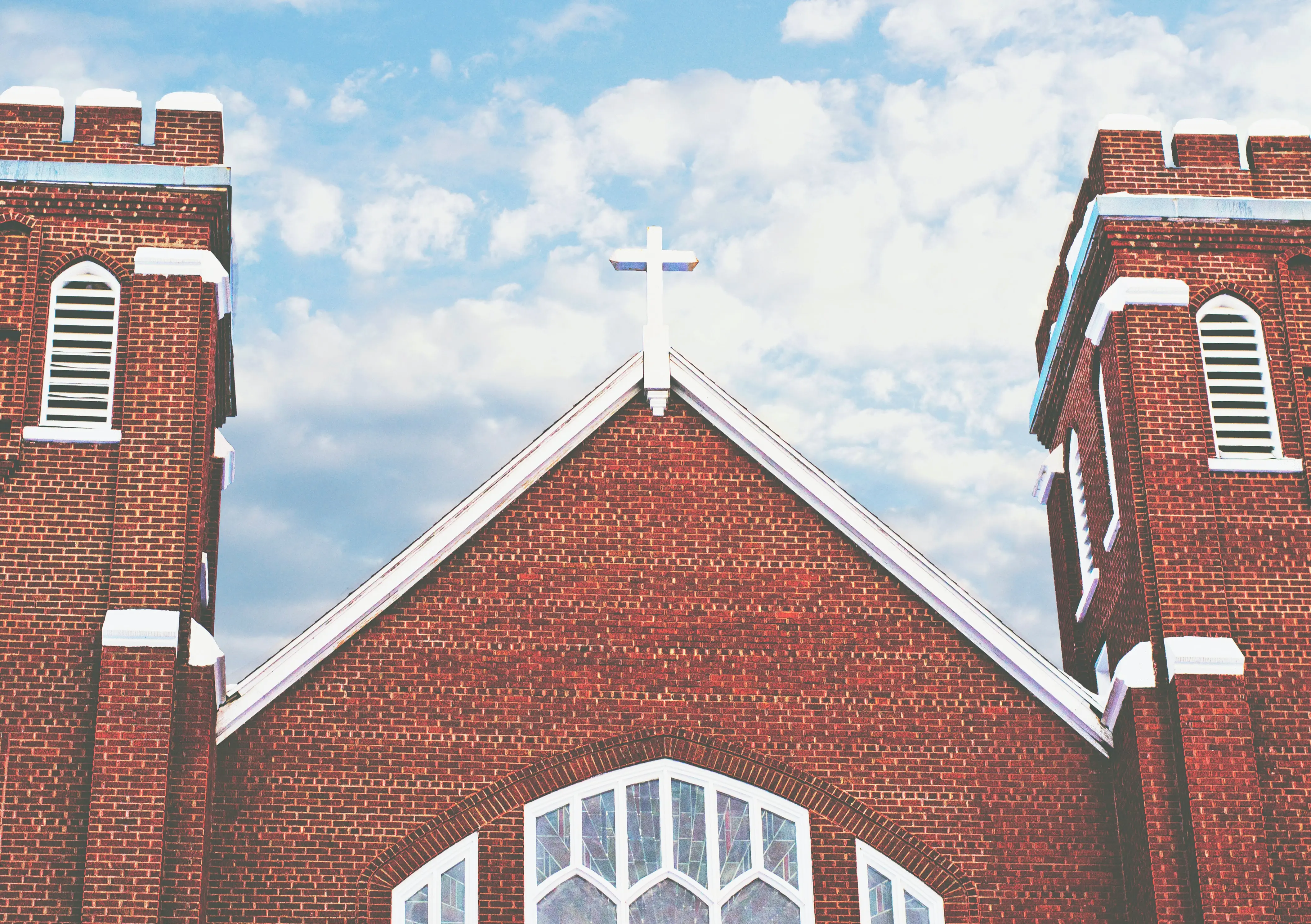 Red brick church with white cross on roof