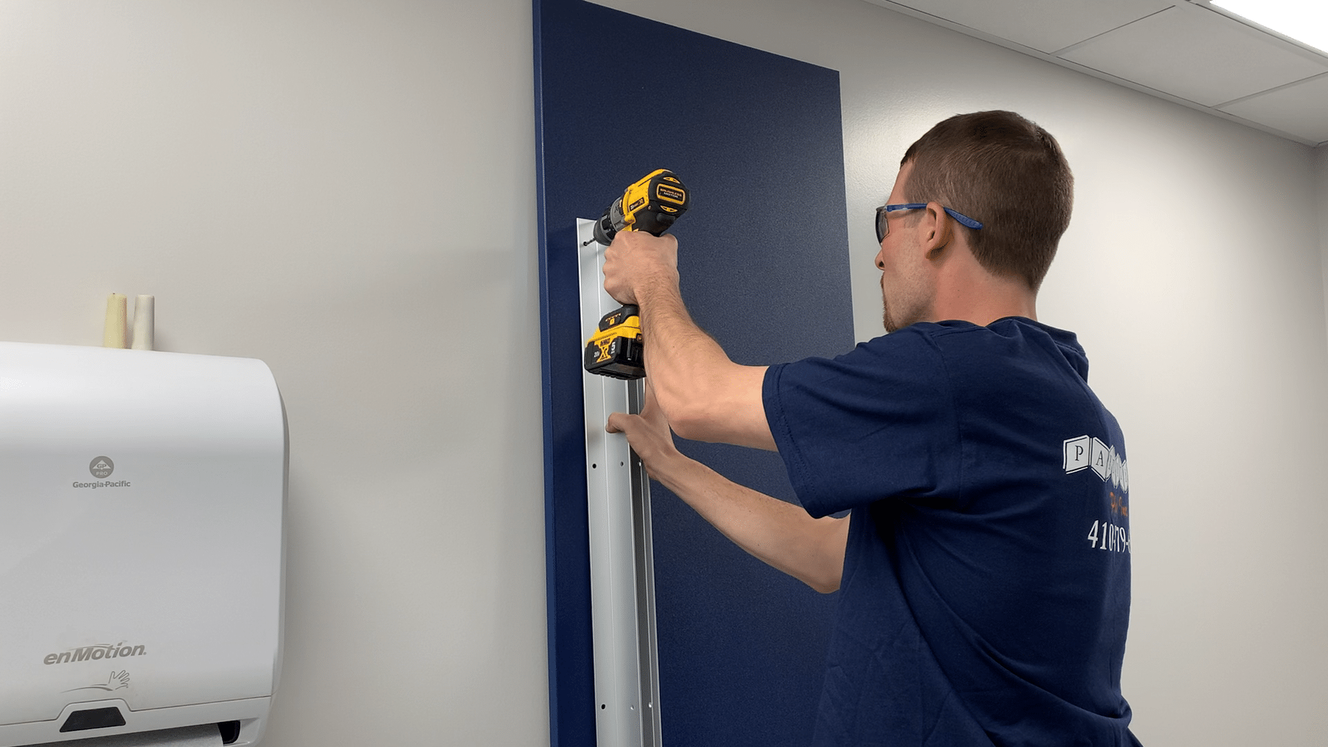 Photo of a Partition Plus employee attaching a continuous bracket to a toilet partition pilaster 