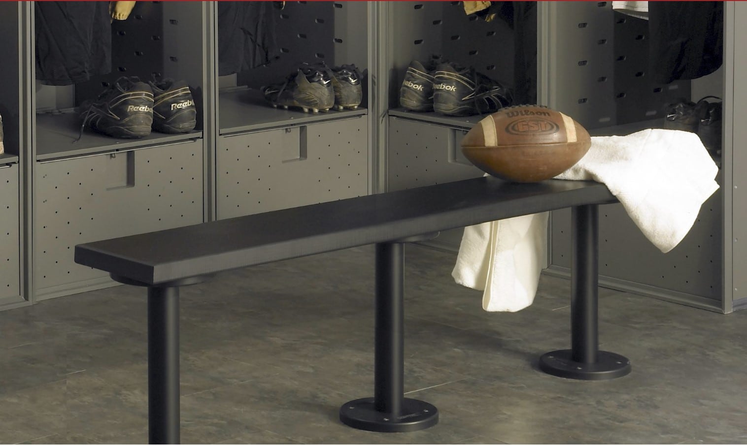 Black HDPE solid plastic locker room bench with a football and towel on top