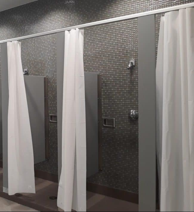 Grey shower stalls with white curtains attached