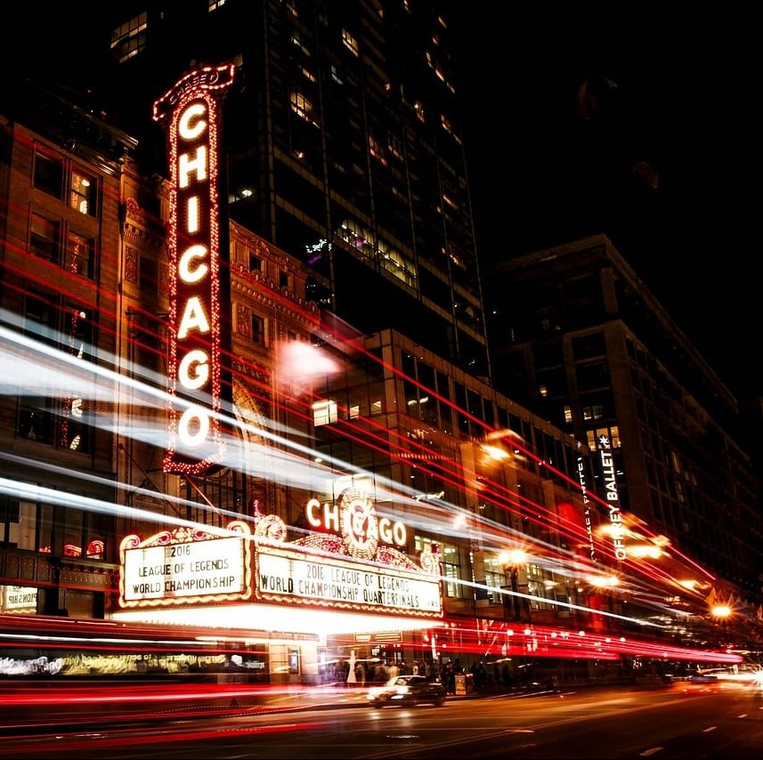 Fast moving traffic causes light streaks in this photo of a downtown theater. Partition Plus provides fast quotes on bathroom stalls in Chicago and surrounding areas. Photograph of Chicago theater, night with light trails in street.