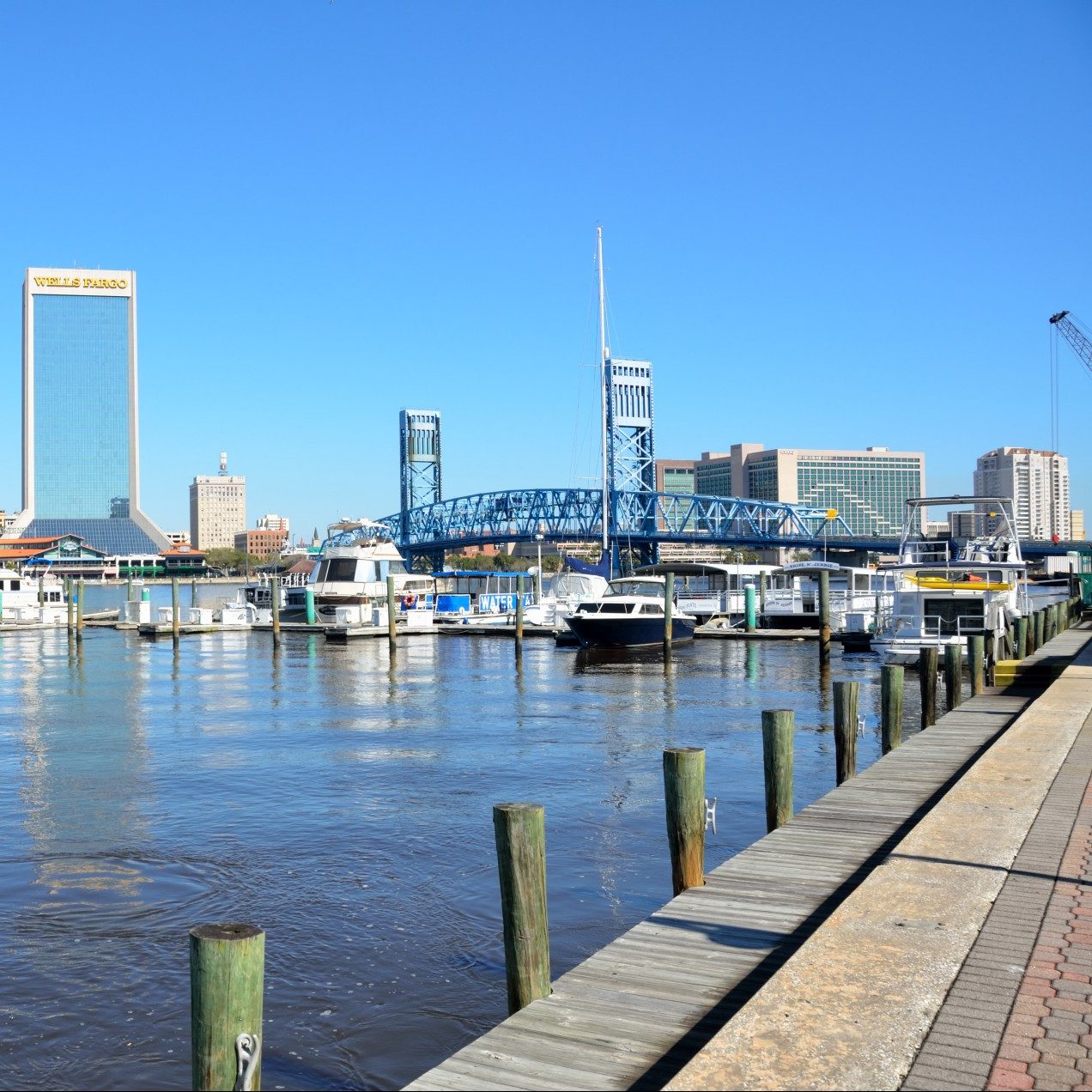 Photograph of Jacksonville, Florida harbor, boats, city skyline in background.
