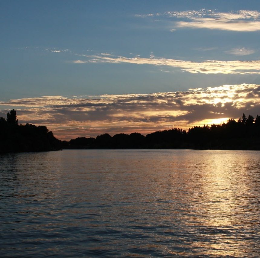 Photograph of the sunset over the Sacramento River delta, trees.