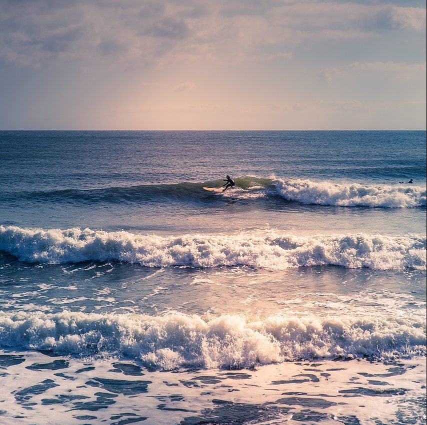 Photograph of Rhode Island’s blue tinted, rough surf, with surfer.