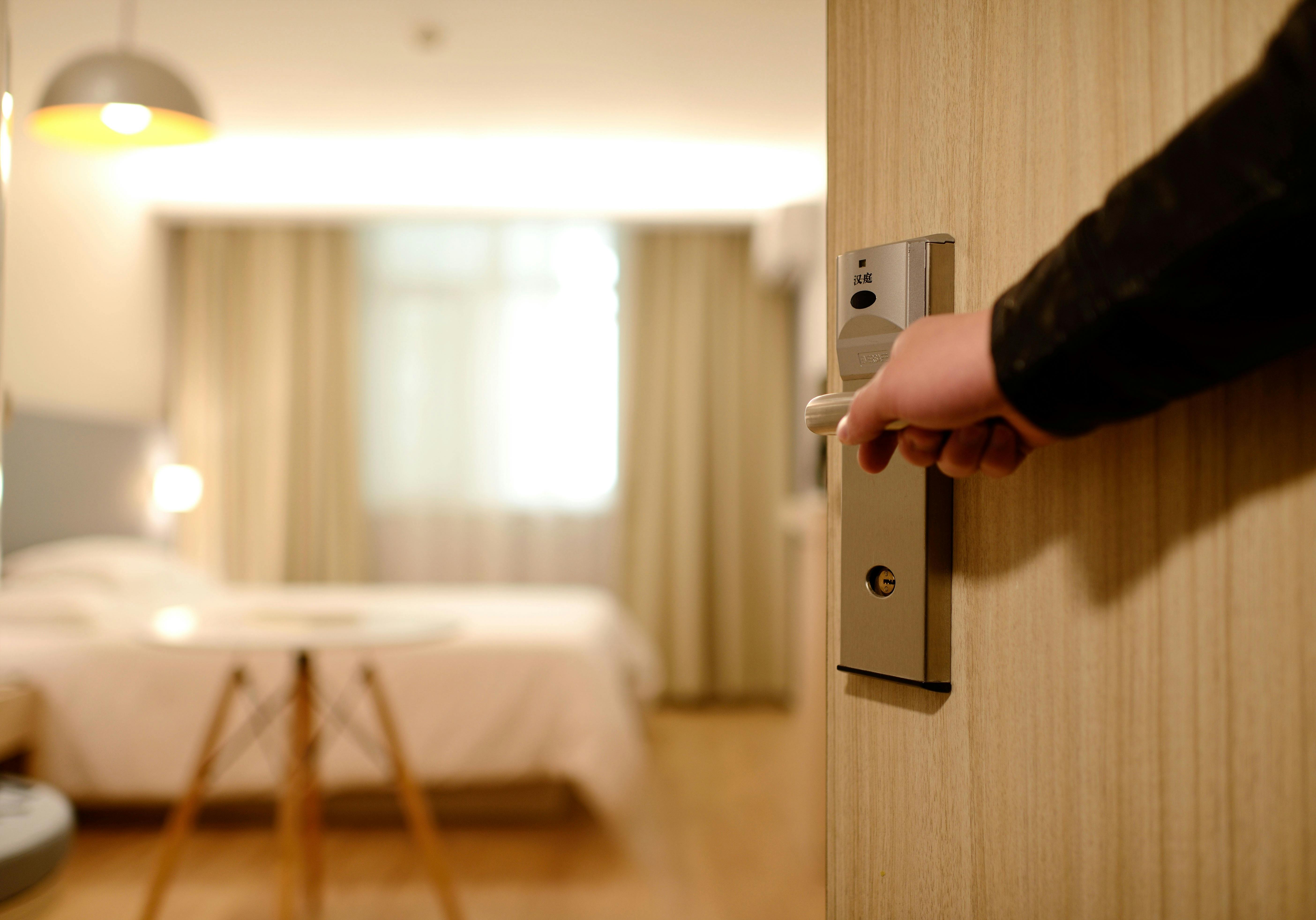 Hand opening the door to a hotel room